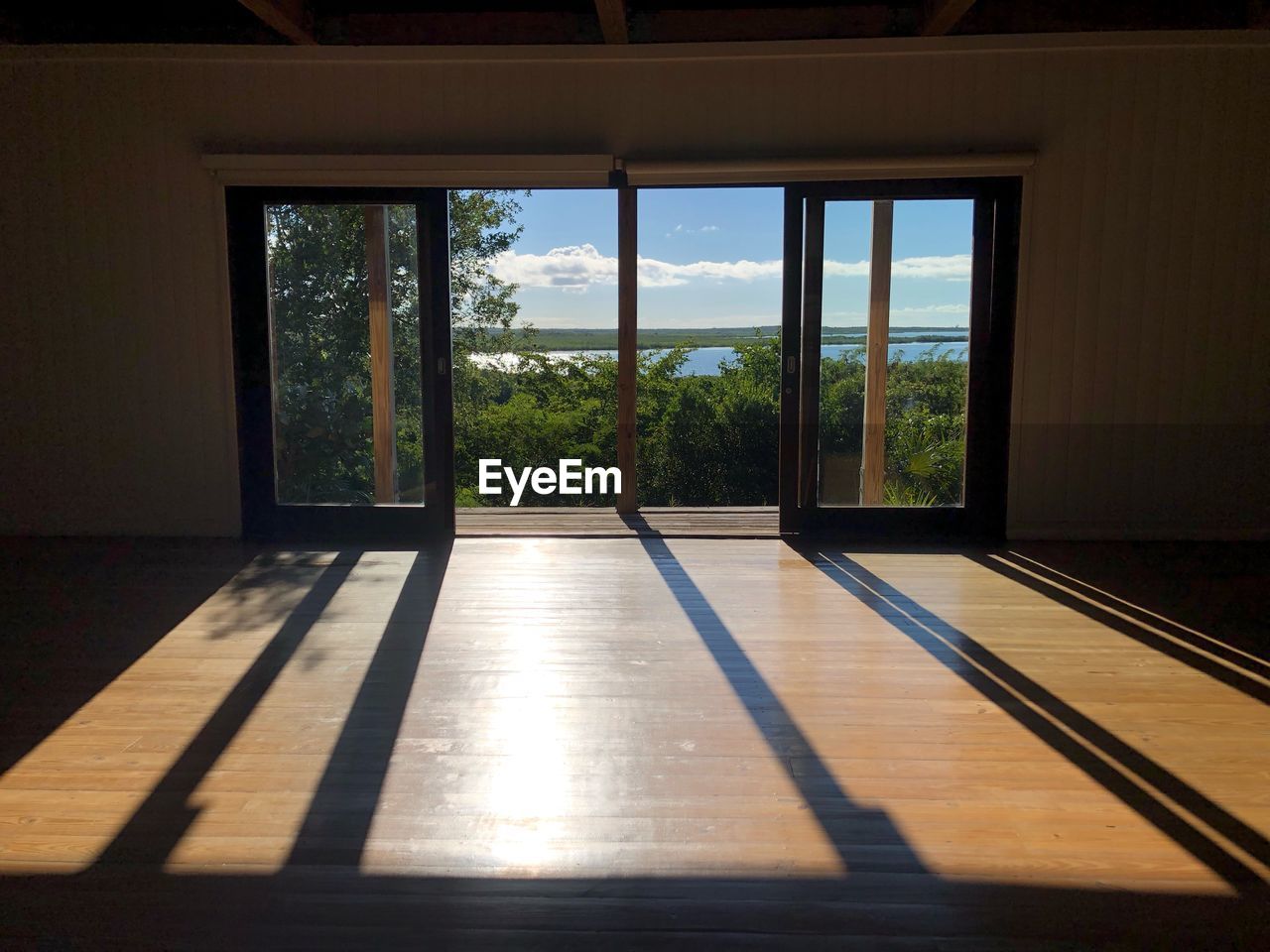 Sea and trees  seen through window of building with a sunlight shadow 