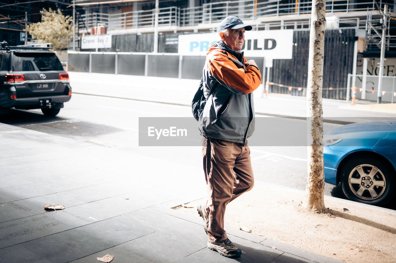 REAR VIEW OF MAN WITH UMBRELLA ON ROAD