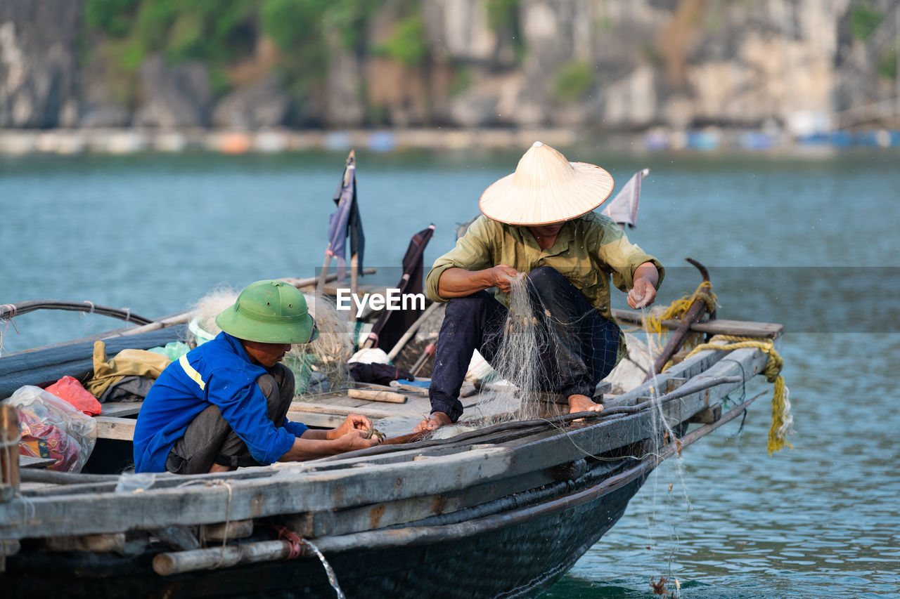 Fishermen placing fishing net on boat at lake