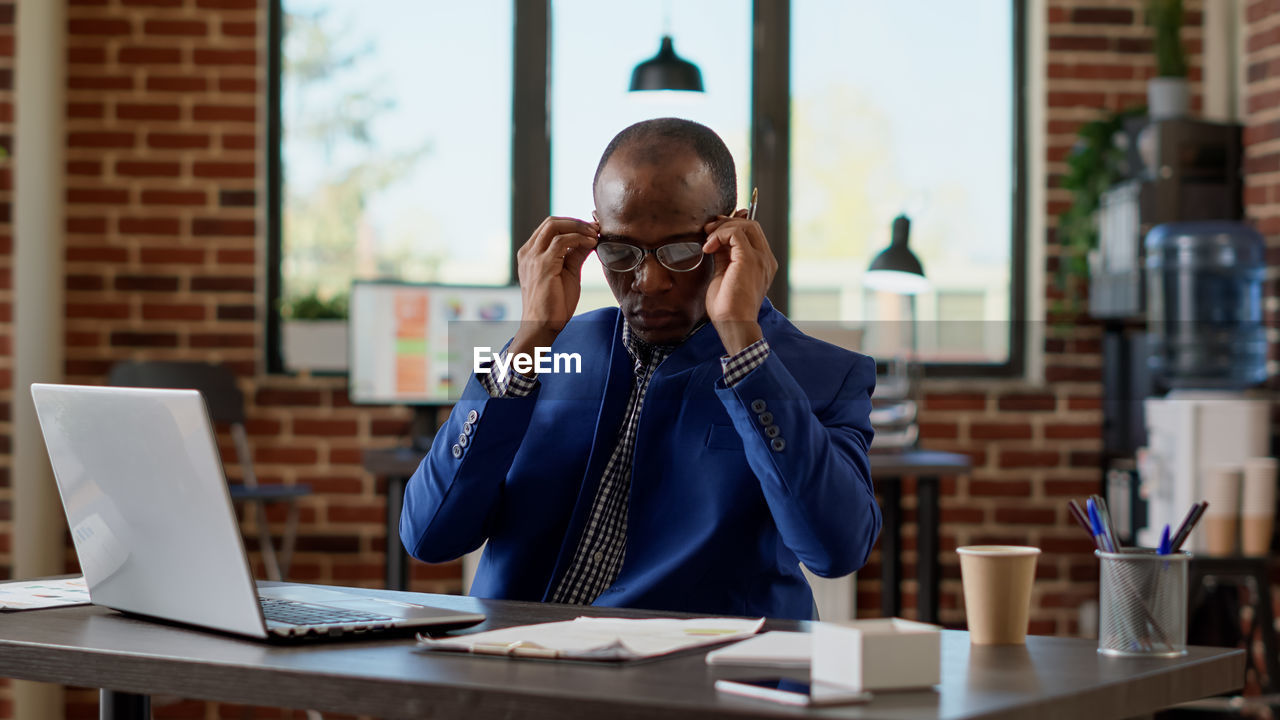 Businessman sitting with laptop at desk in office