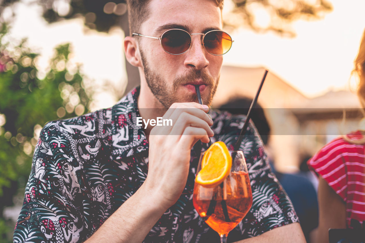 Close-up of young man having drink while sitting at cafe