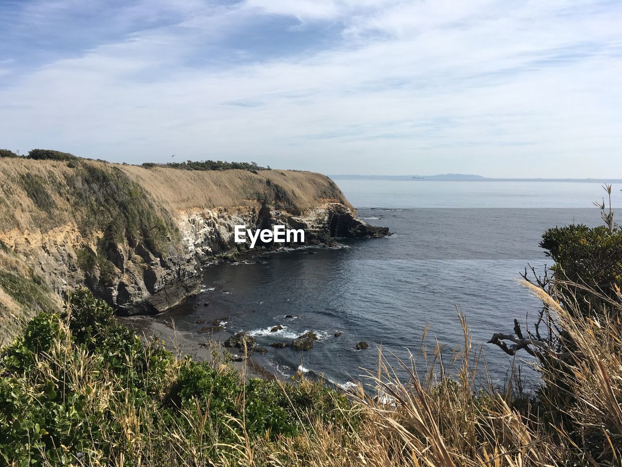 Scenic view of sea and cliff against sky