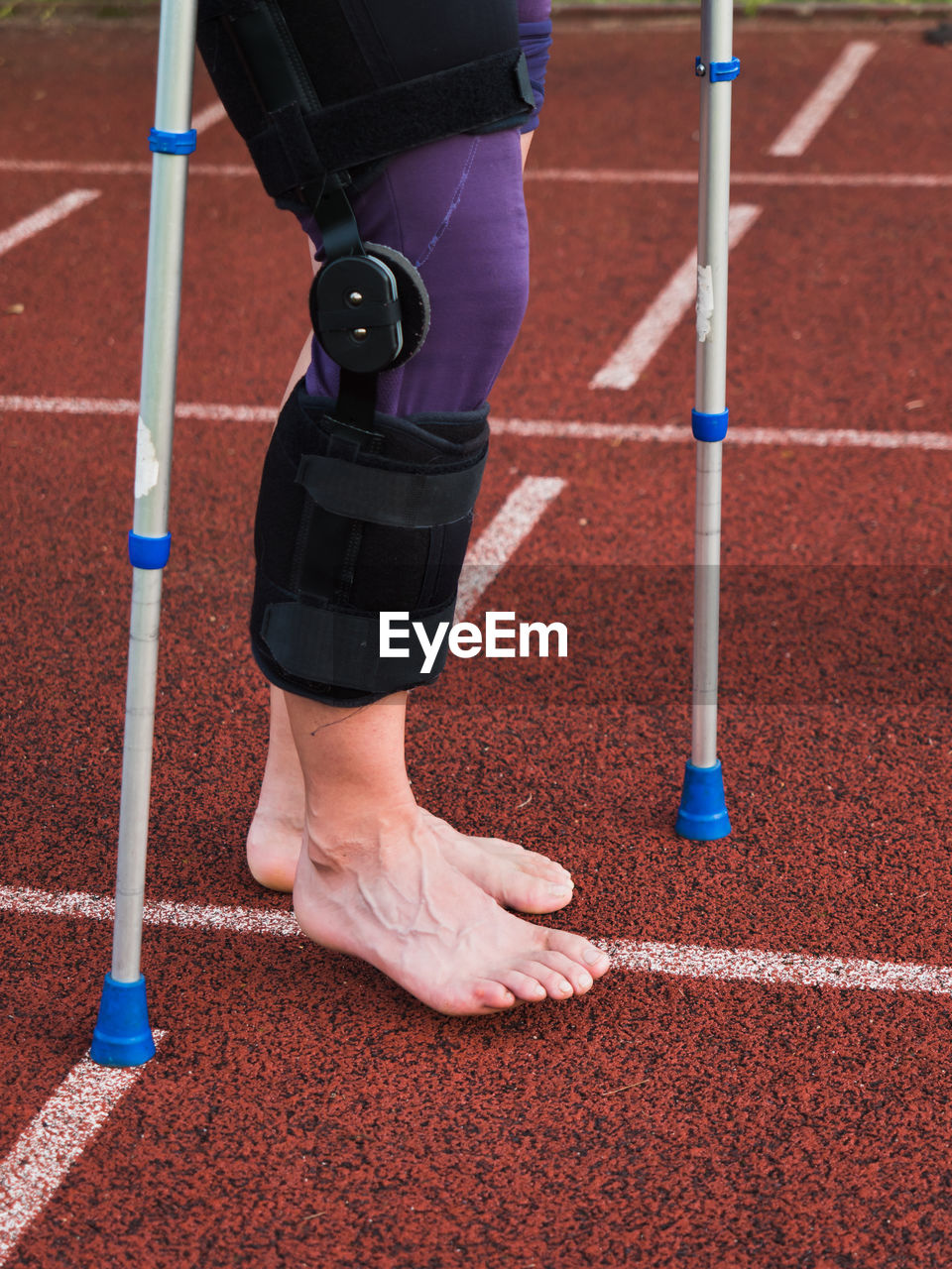 Hurt runner walk by forearm crutches on running track after finished competition on  outdoor stadium