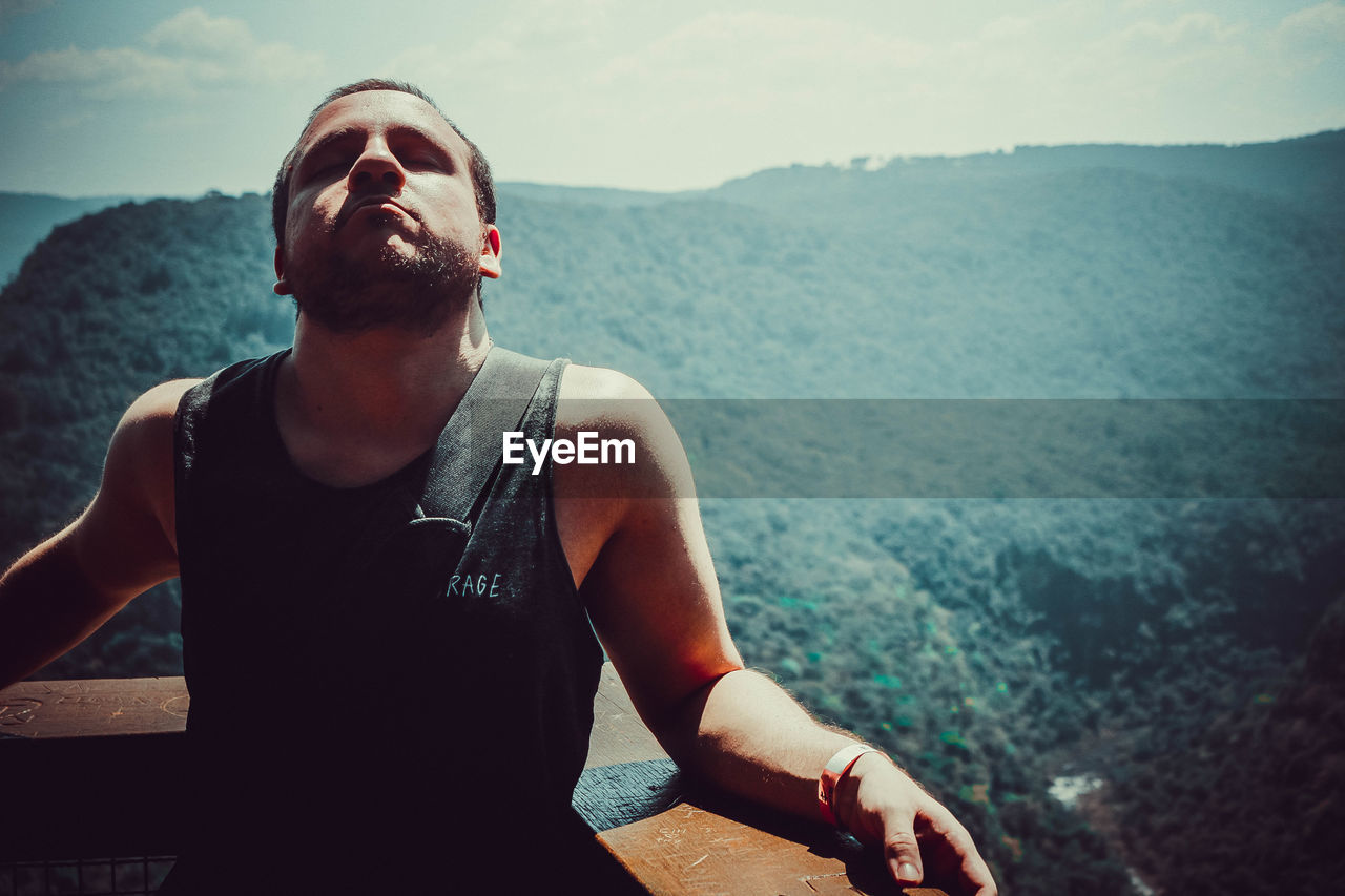 Man standing at observation point against mountain range