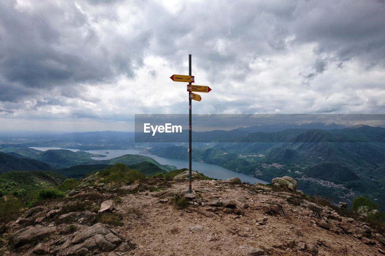 Arrow signs on mountain against sky