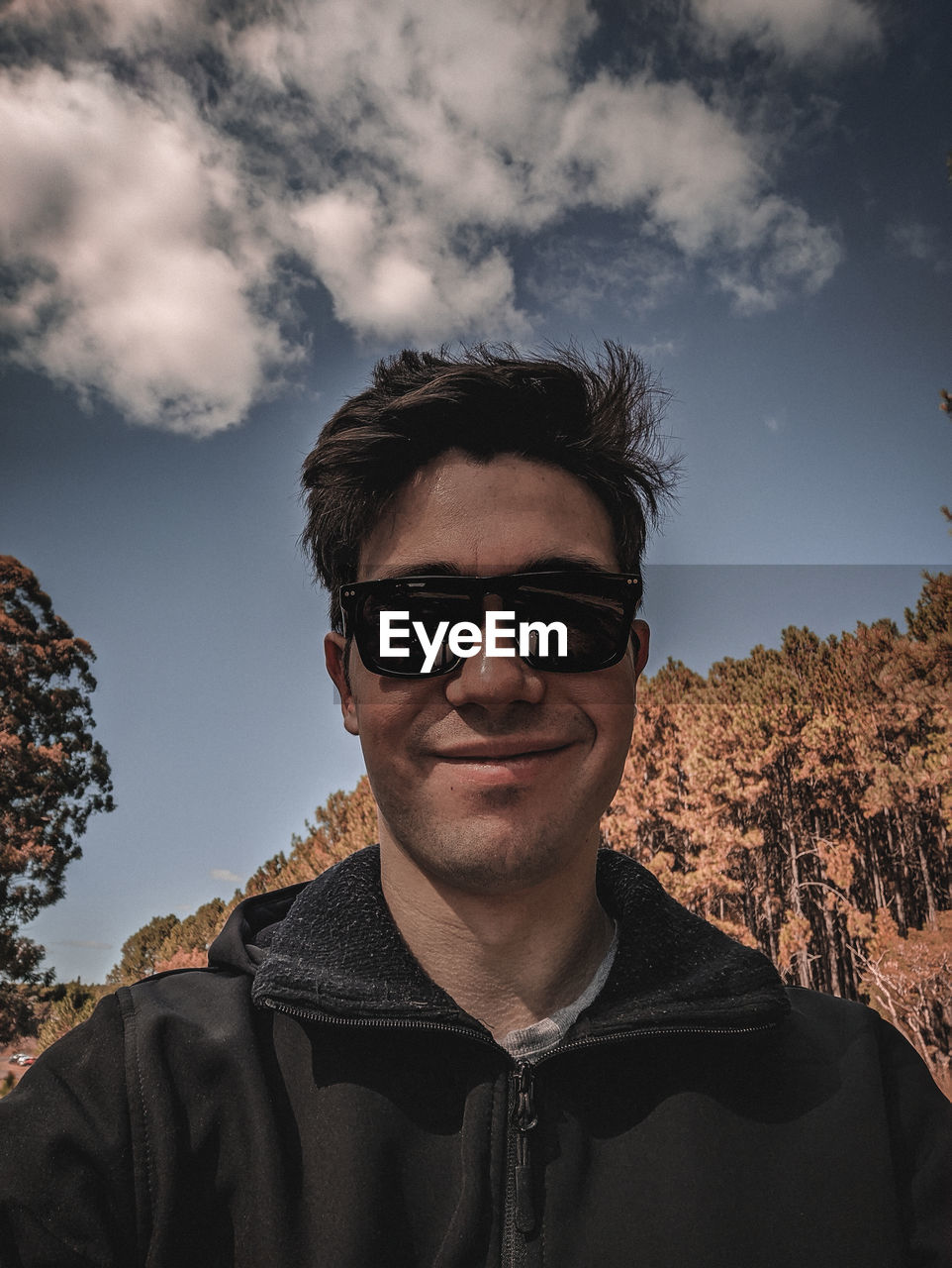 Portrait of young man wearing sunglasses against sky