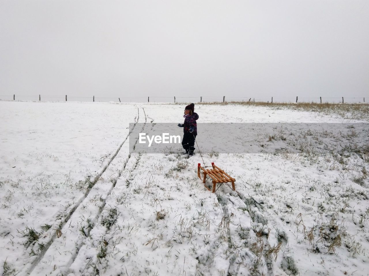 rear view of man walking on snow covered field against clear sky