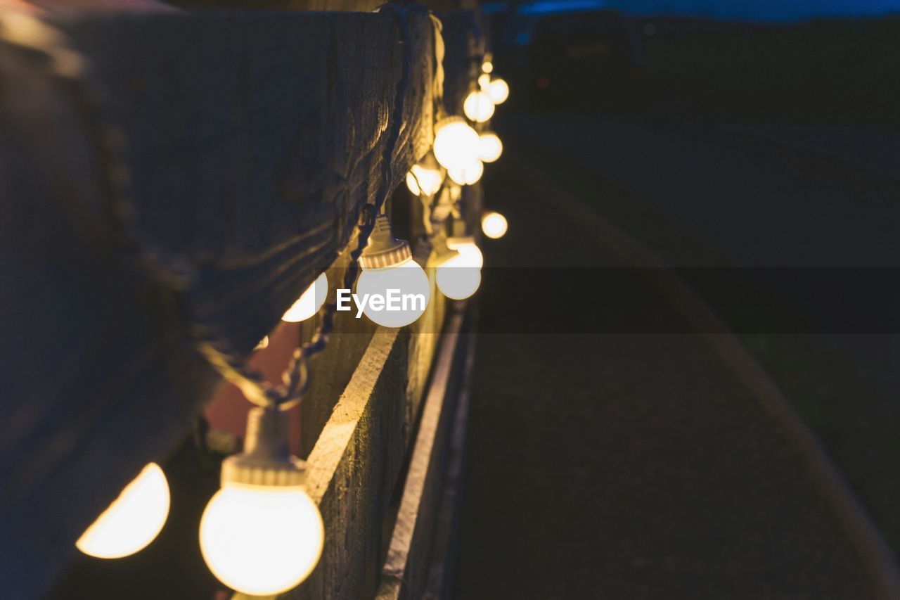 CLOSE-UP OF ILLUMINATED LIGHT BULB HANGING