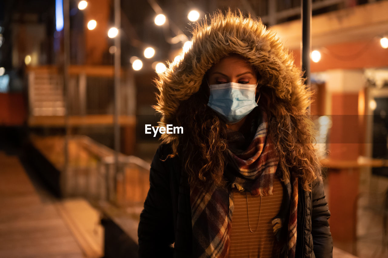 Portrait of woman wearing a mask at night in the city in 2020