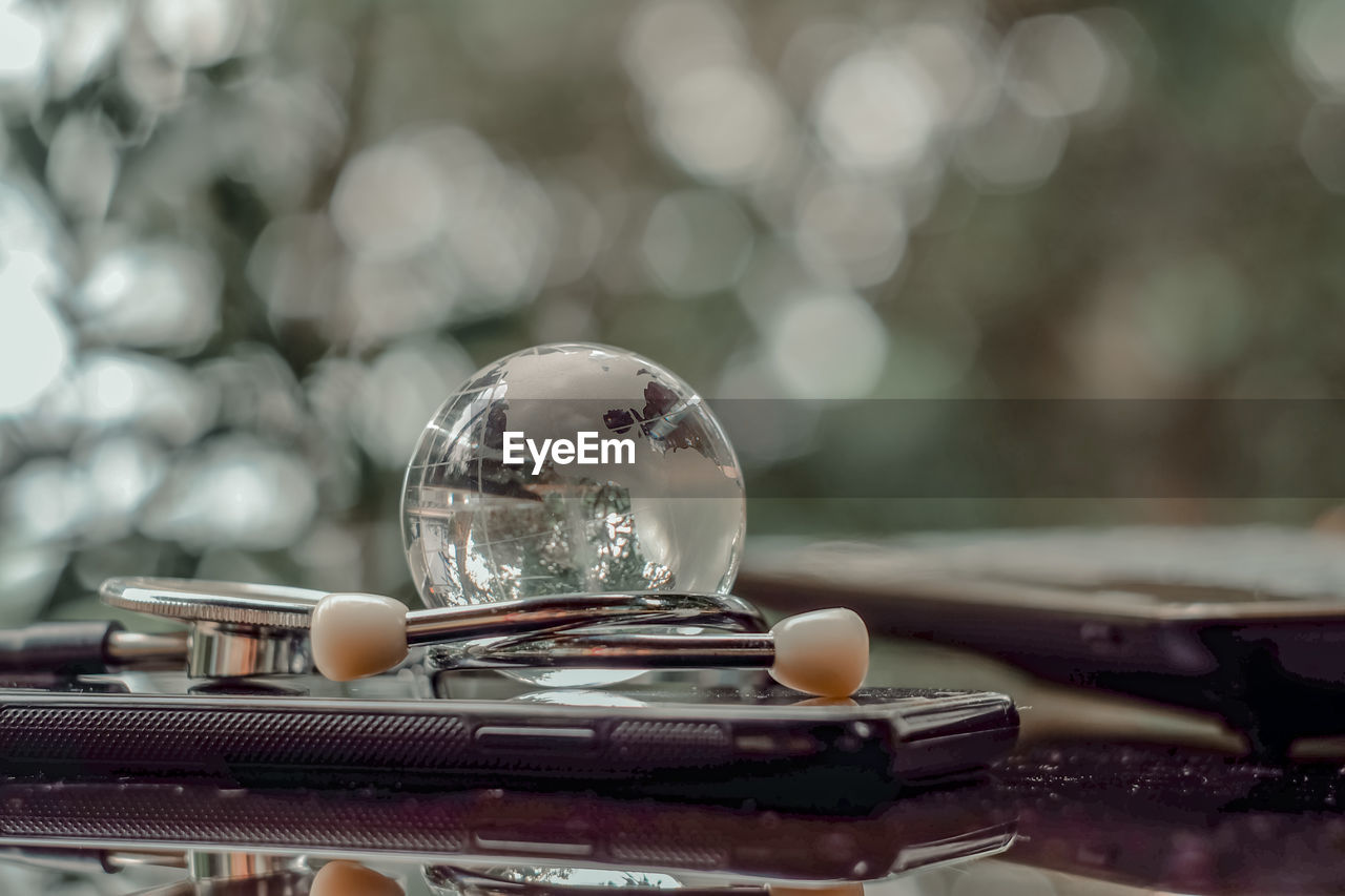 CLOSE-UP OF CRYSTAL BALL ON TABLE AGAINST BLURRED BACKGROUND