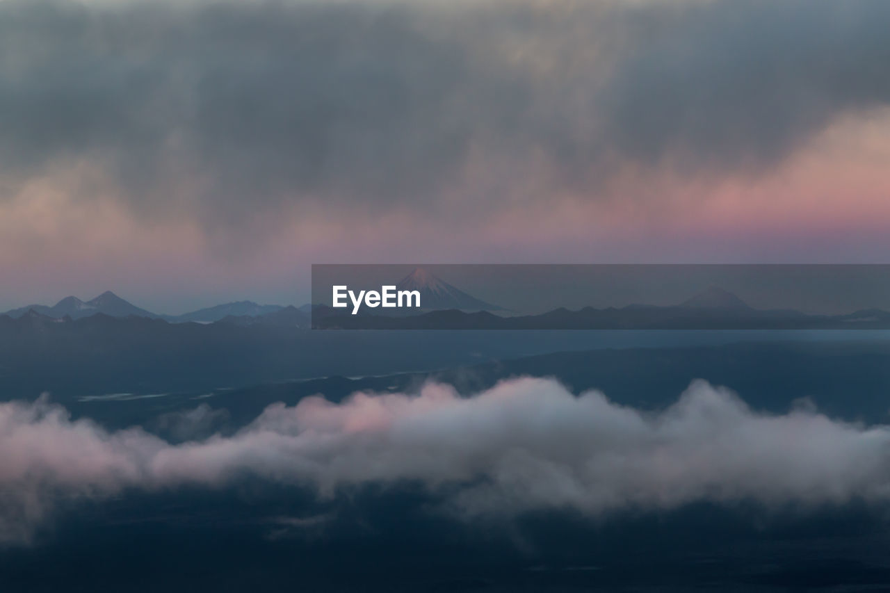 SCENIC VIEW OF MOUNTAINS AGAINST CLOUDY SKY DURING SUNSET