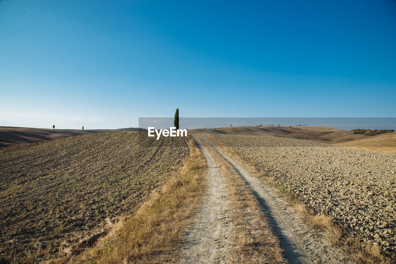 Dirt road against clear blue sky