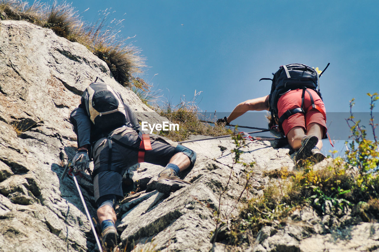 Low angle view of friends climbing on rock formation