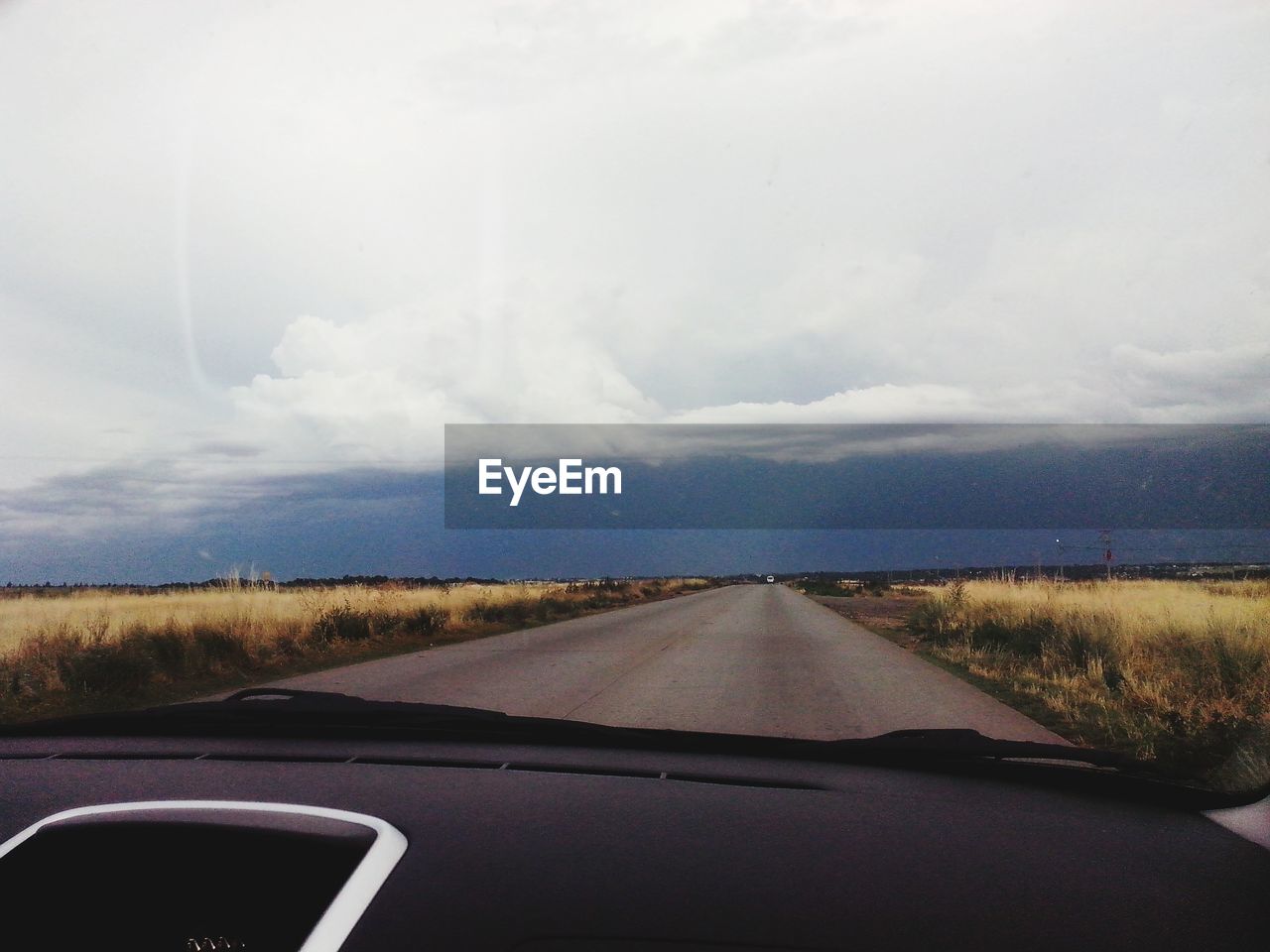 Country road against sky seen through car windshield