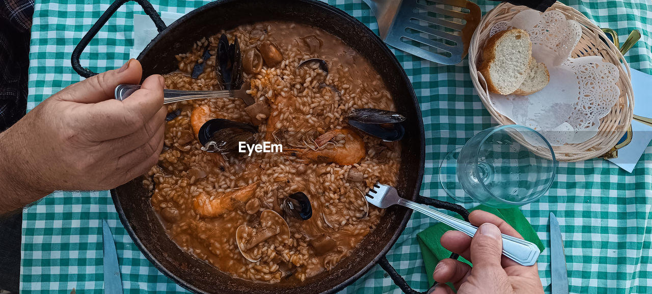 Friends eating rice paella with seafood. valencian tradition