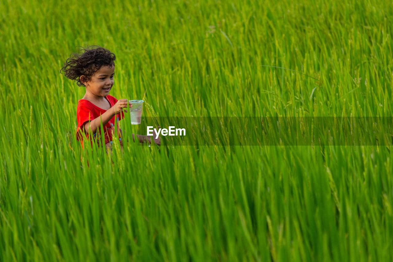 Girl holding glass on grassy field