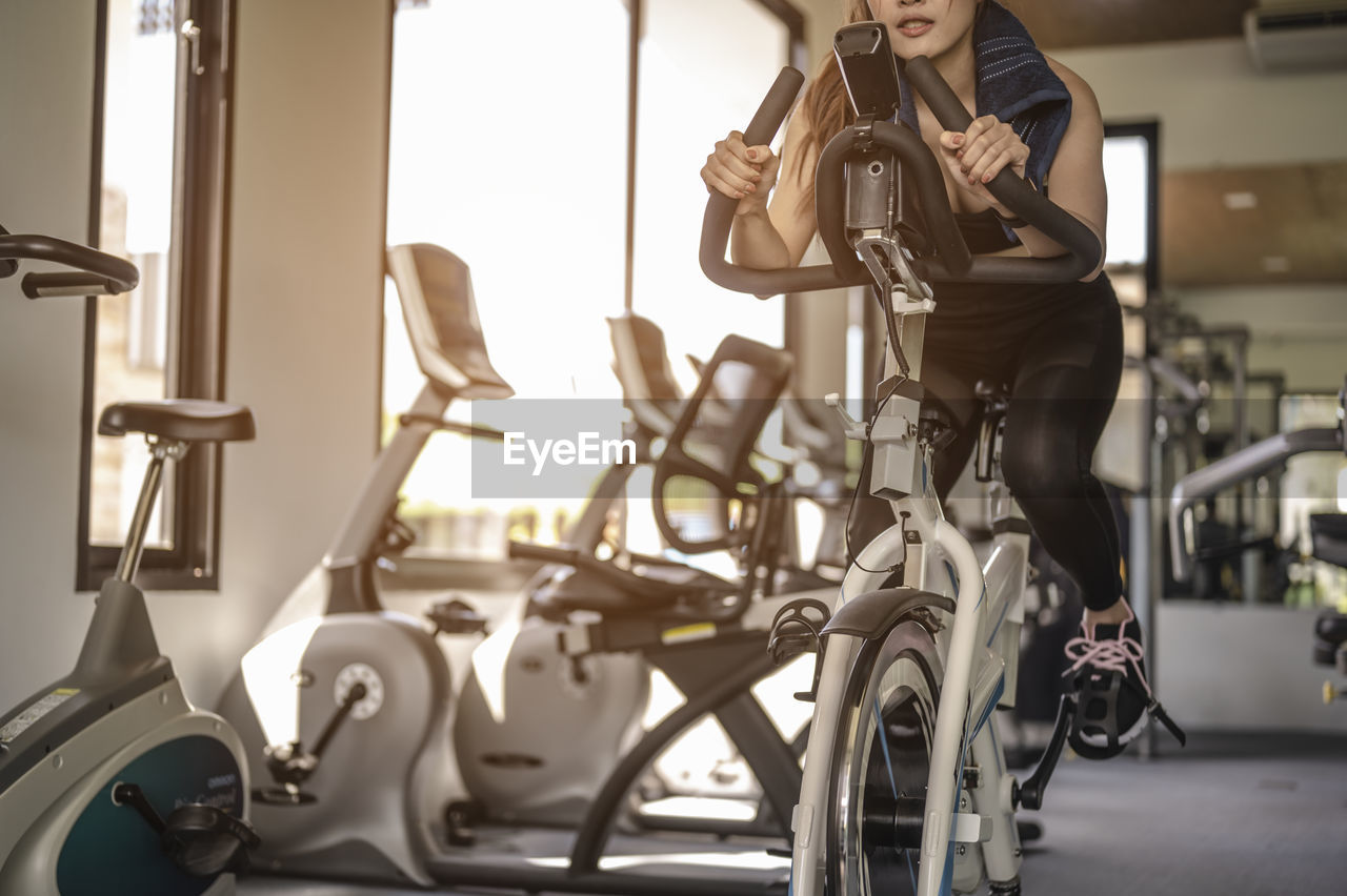 Woman exercising while cycling in gym
