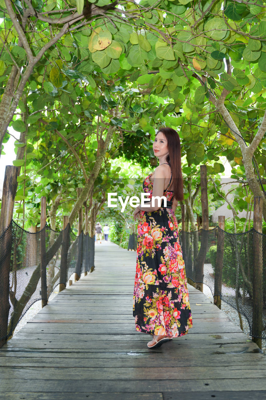 Full length portrait of beautiful woman in black dress standing in the garden