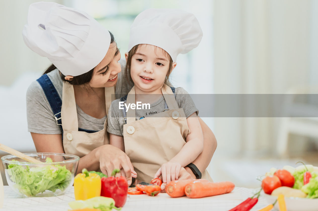 Mother and daughter preparing food on table