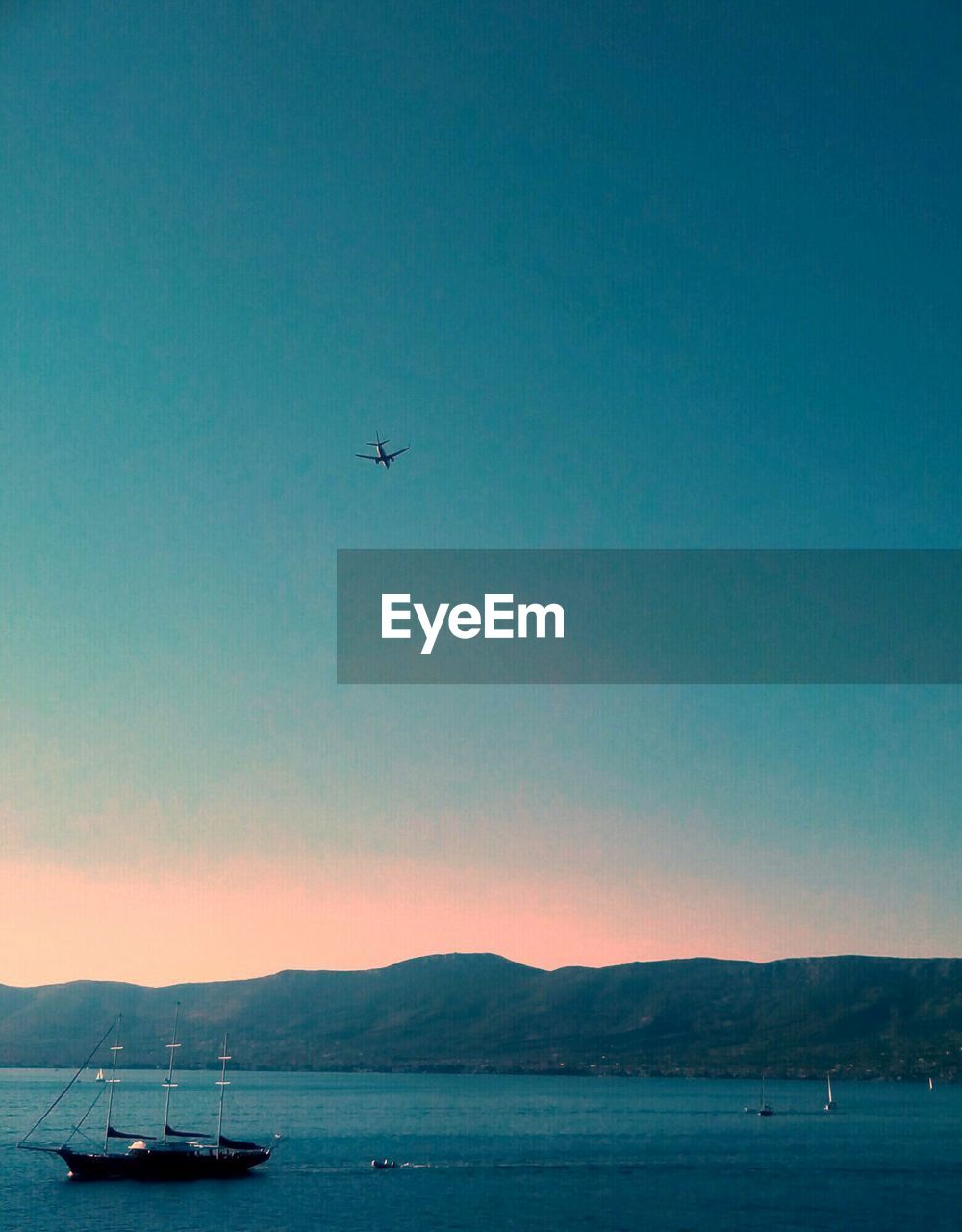 AIRPLANE FLYING OVER SEA AGAINST SKY