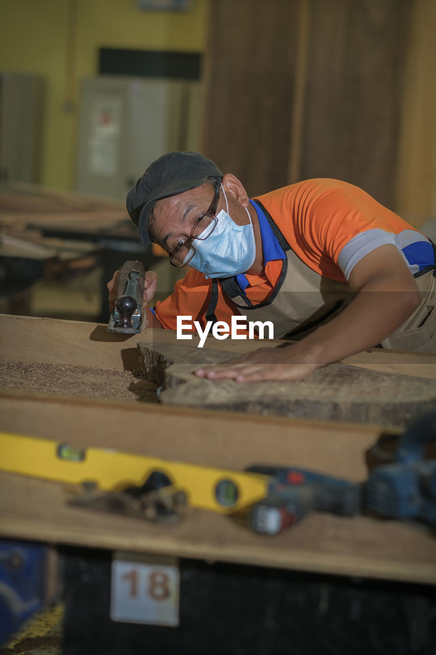 Carpenter wearing mask working at workshop