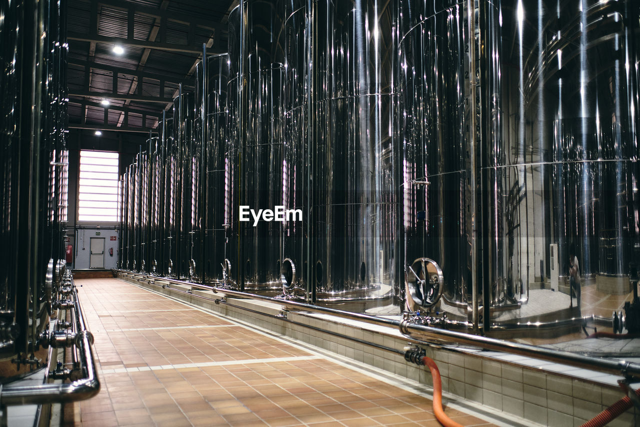 Rows of shiny stainless steel reservoirs placed in bright industrial area of modern factory