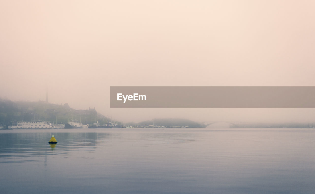 Scenic view of lake against sky during foggy weather