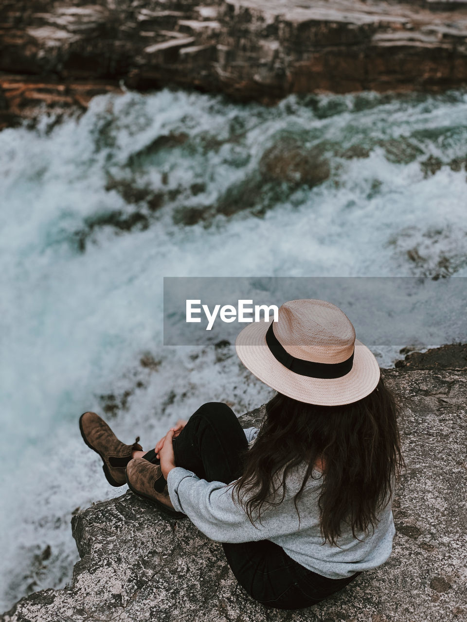 High angle view of woman sitting on rock near waterfall at crescent falls, alberta 