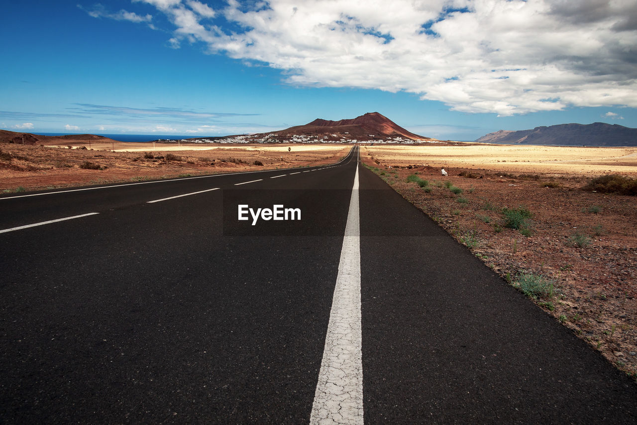 Road leading towards mountain range against sky