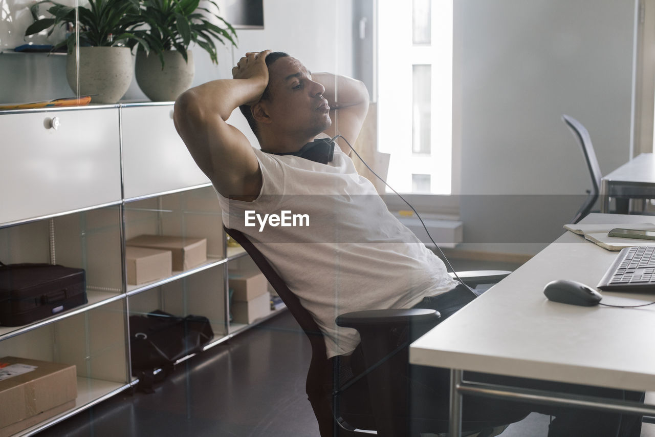 Overworked male entrepreneur with head in hand sitting on chair at office