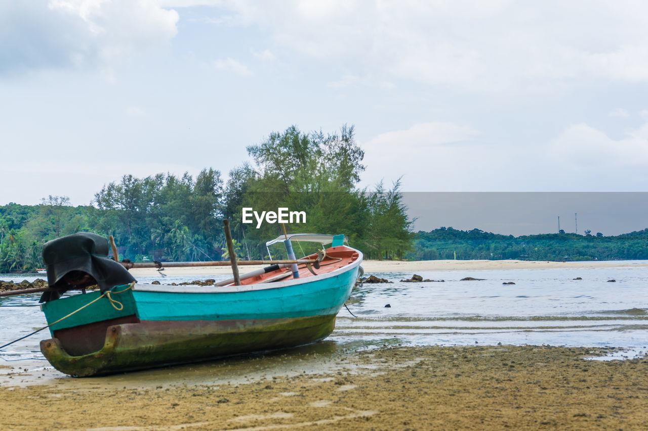 BOATS MOORED ON SHORE AGAINST SKY