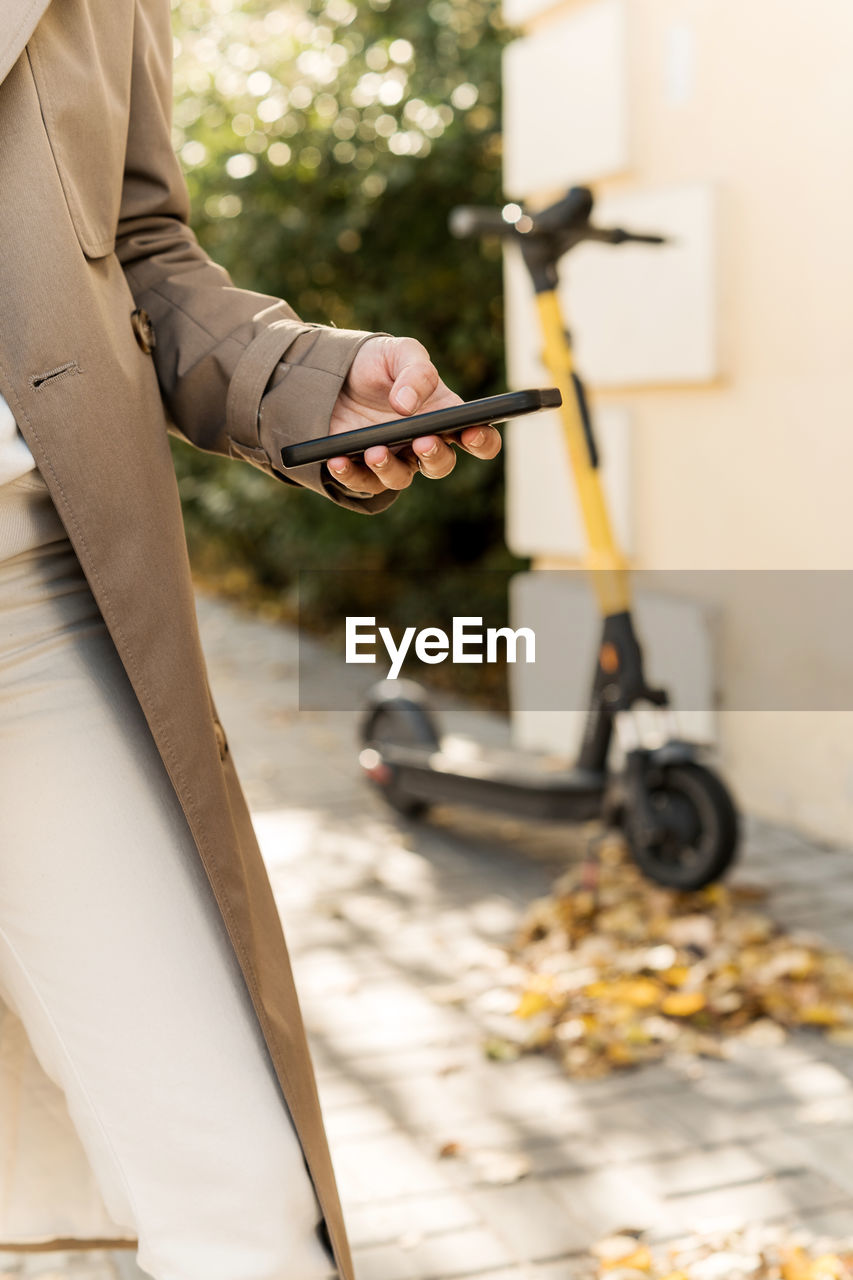 Woman using mobile phone to rent an electric vehicle. female using mobile device in the city