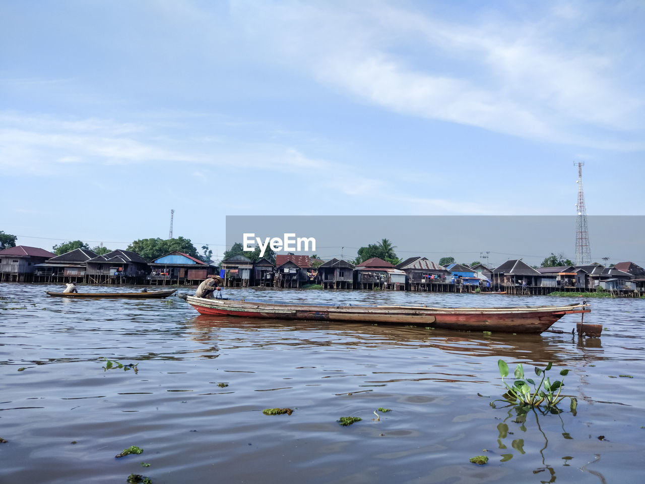 Man sitting in boat on lake against sky