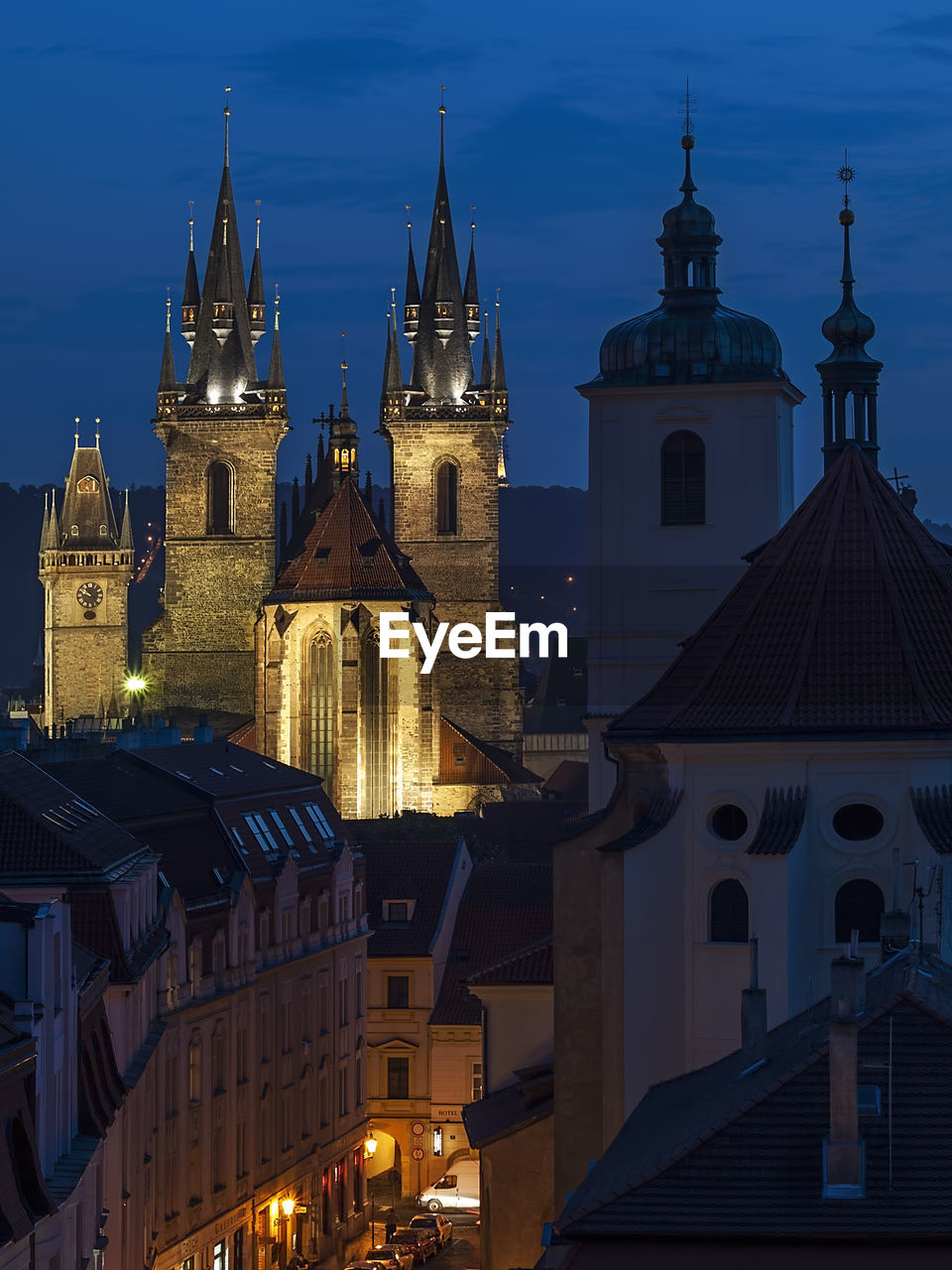 Illuminated cathedral by buildings in city against sky