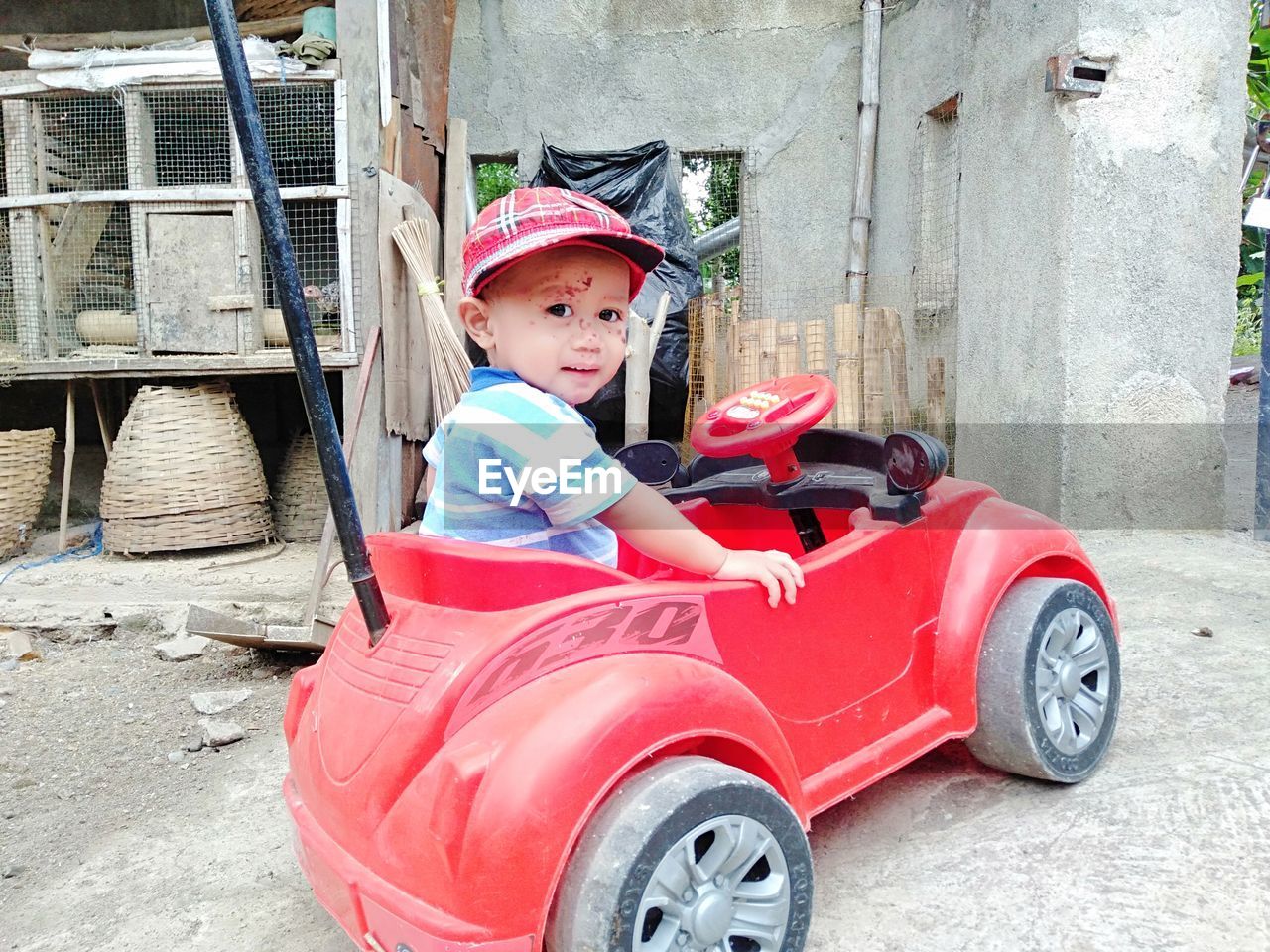 PORTRAIT OF CUTE BOY SITTING ON RED OUTDOORS