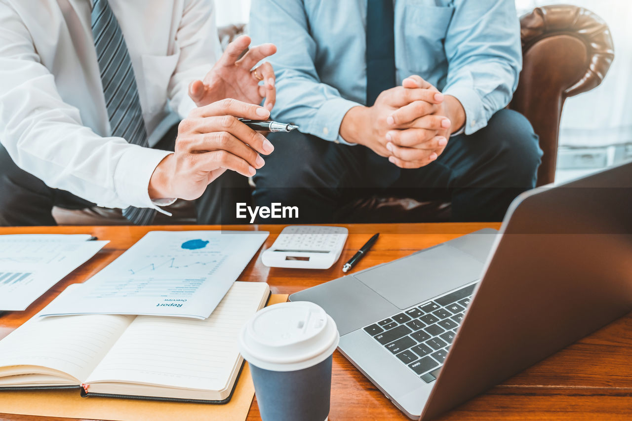 Midsection of business colleagues working at desk in office