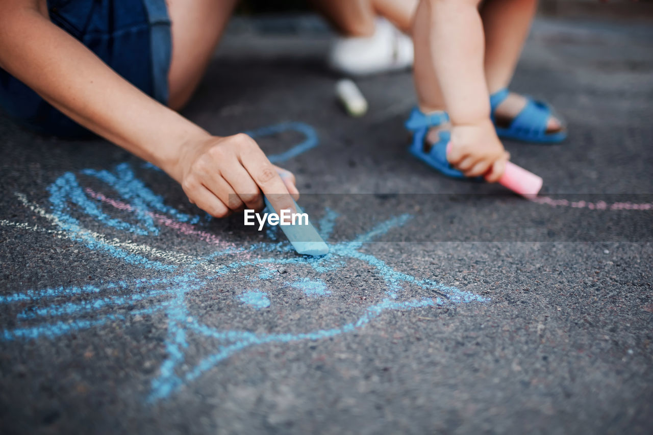 LOW SECTION OF CHILD PLAYING WITH TATTOO ON HANDS