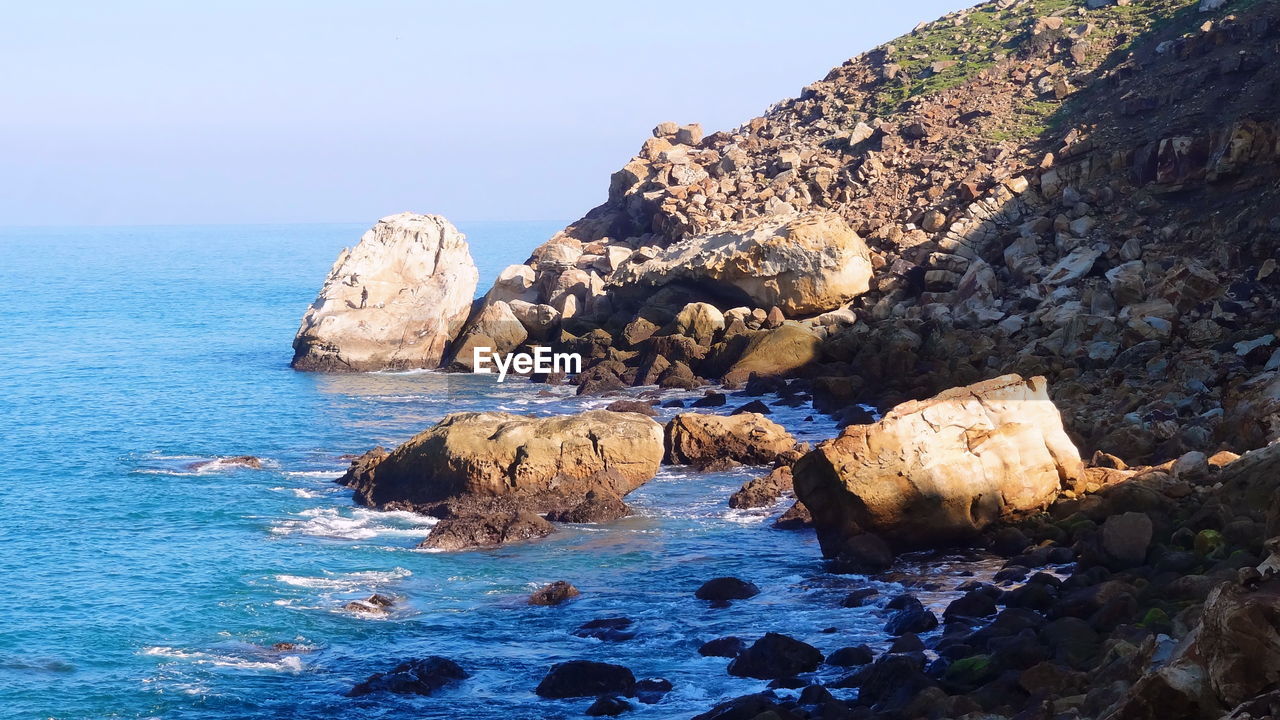 Rocks on sea shore against sky