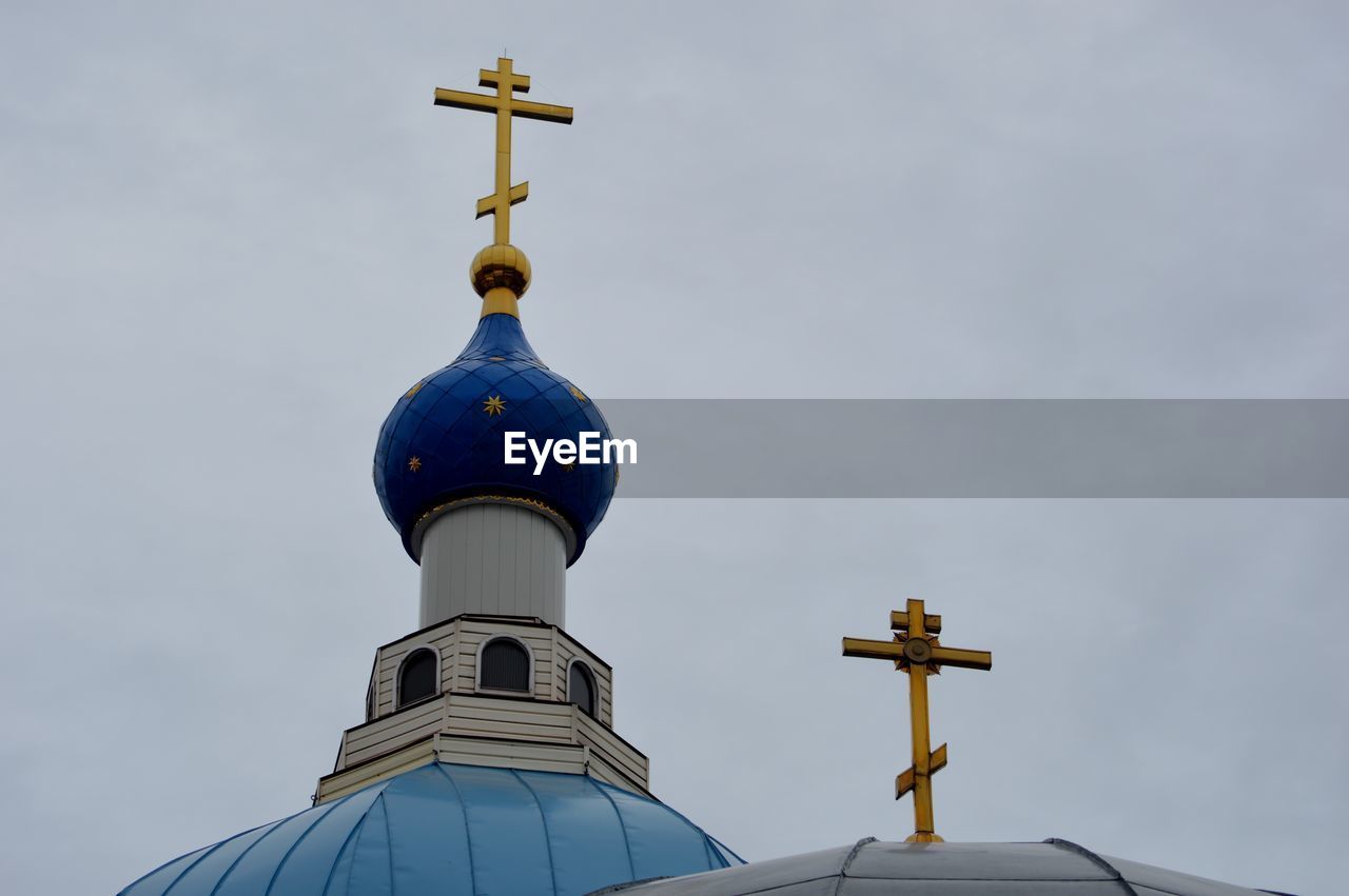 Low angle view of cross by building against sky