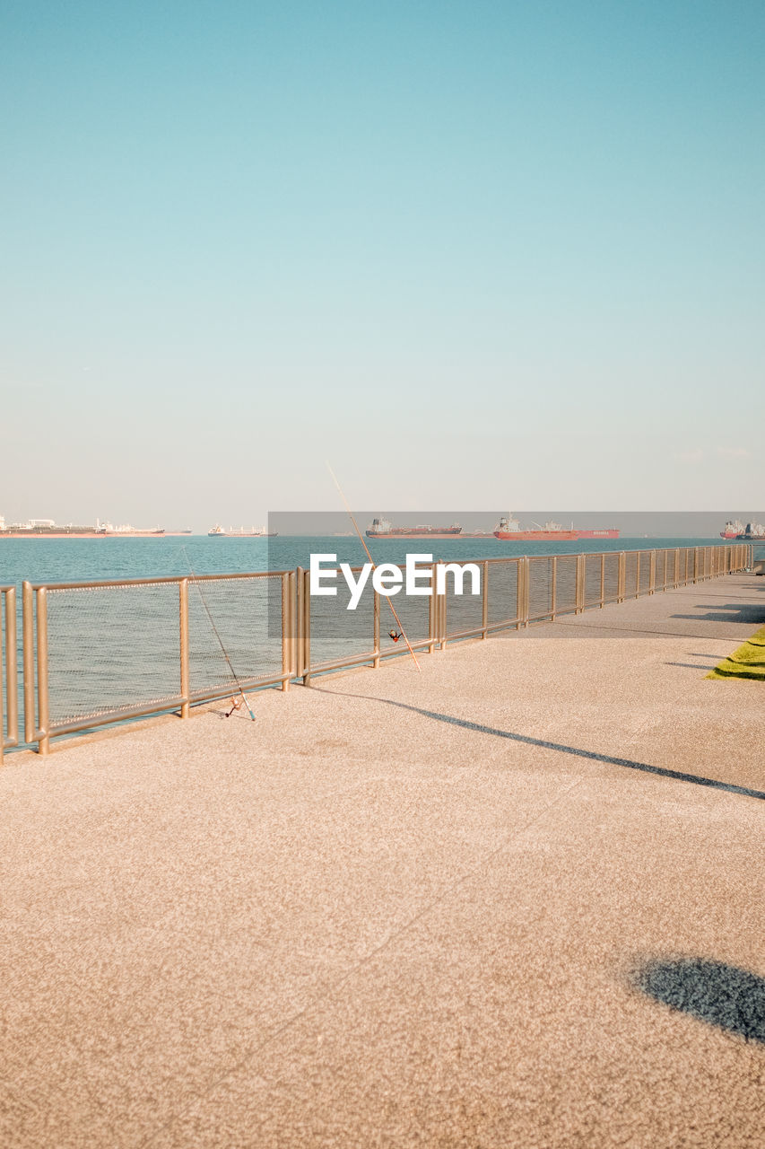 sky, sea, water, horizon, beach, walkway, nature, land, sand, clear sky, coast, copy space, shore, blue, boardwalk, sunny, scenics - nature, architecture, tranquility, no people, horizon over water, ocean, day, sunlight, beauty in nature, tranquil scene, railing, pier, travel, outdoors, travel destinations, built structure, transportation, environment, summer, vacation, morning, landscape, trip, tourism, holiday, bridge, urban skyline, coastline