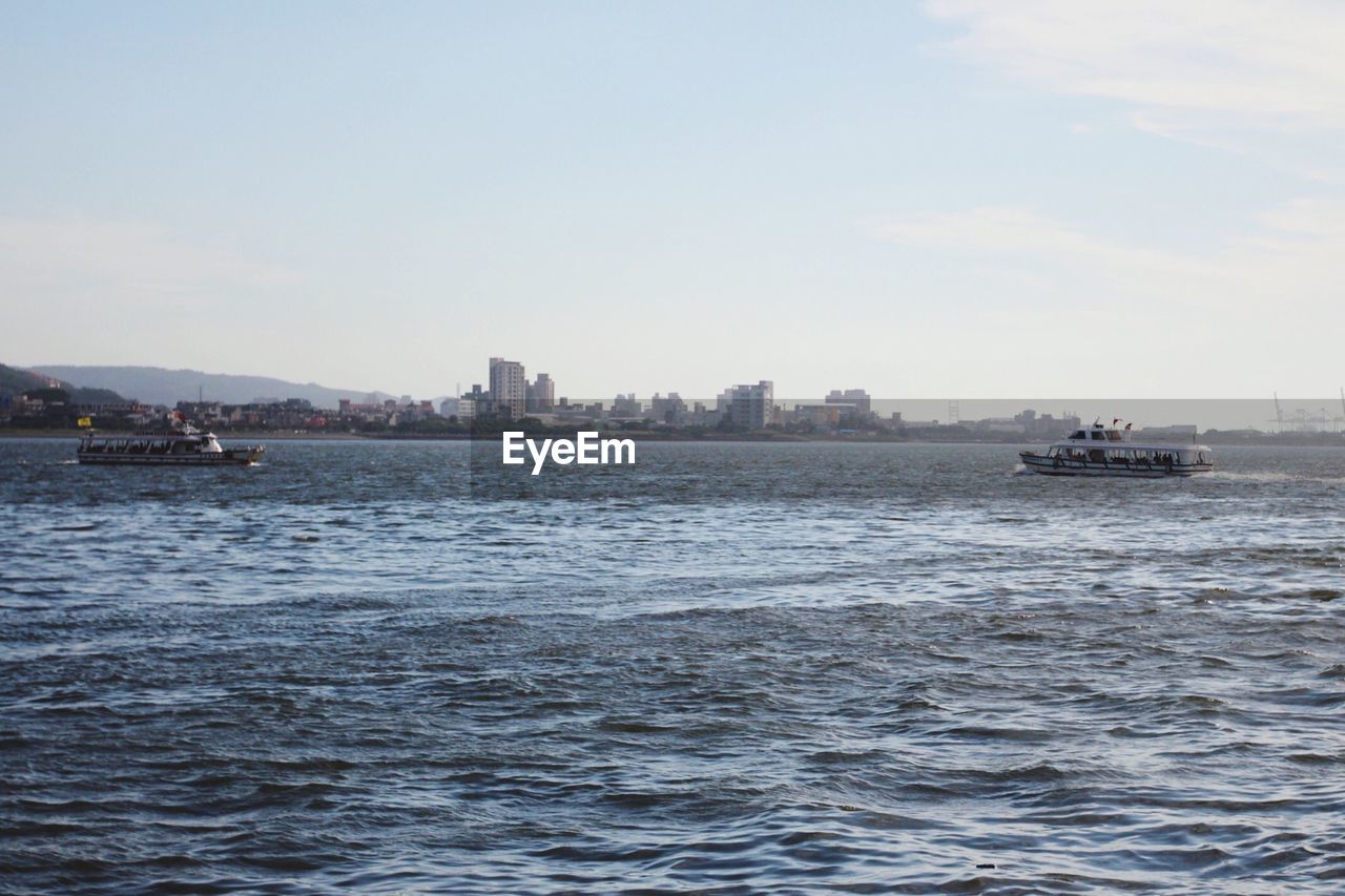 Boats in sea with buildings in background