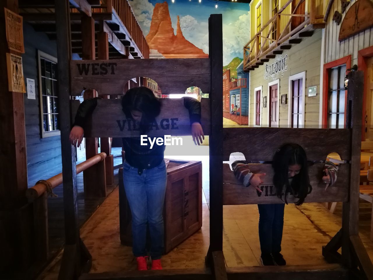 People in pillory against painted image in art studio