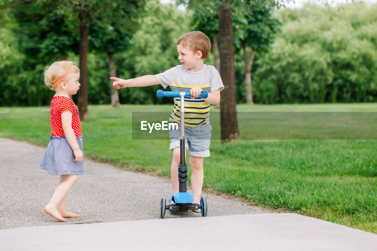 Full length of cute sibling standing on road