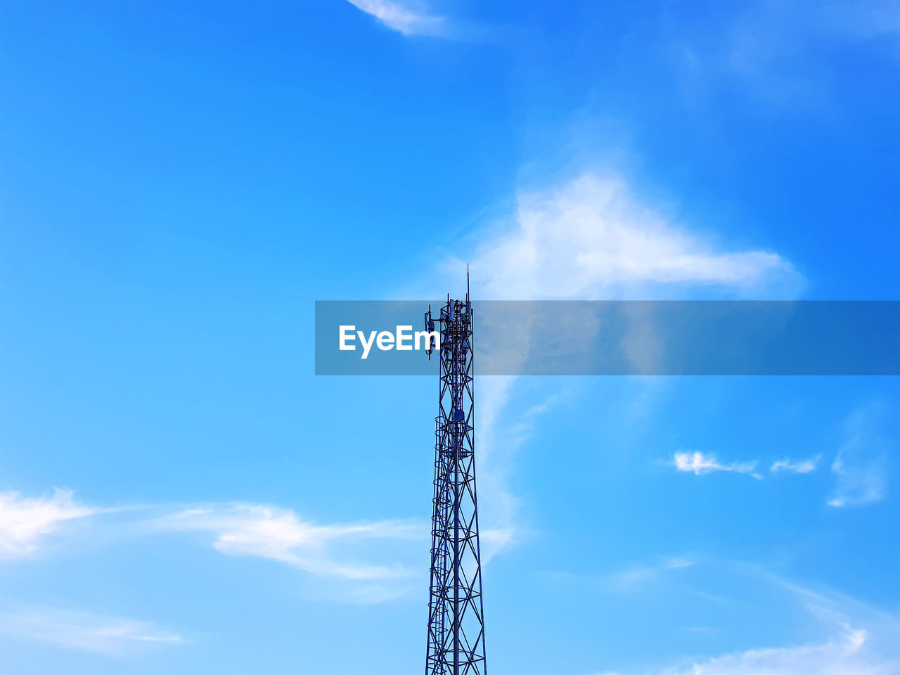 High section of telecommunication tower against blue cloudy sky