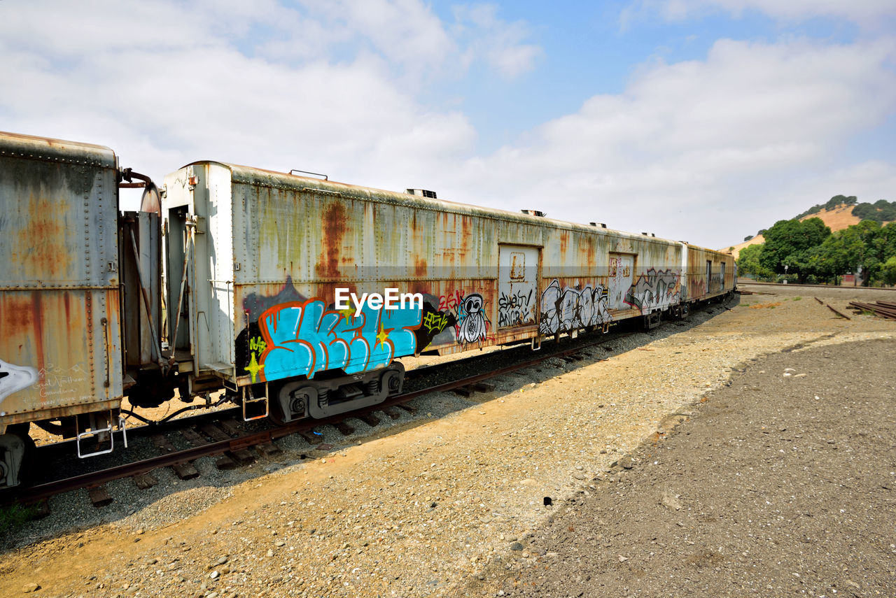 GRAFFITI ON TRAIN AT RAILROAD STATION AGAINST SKY