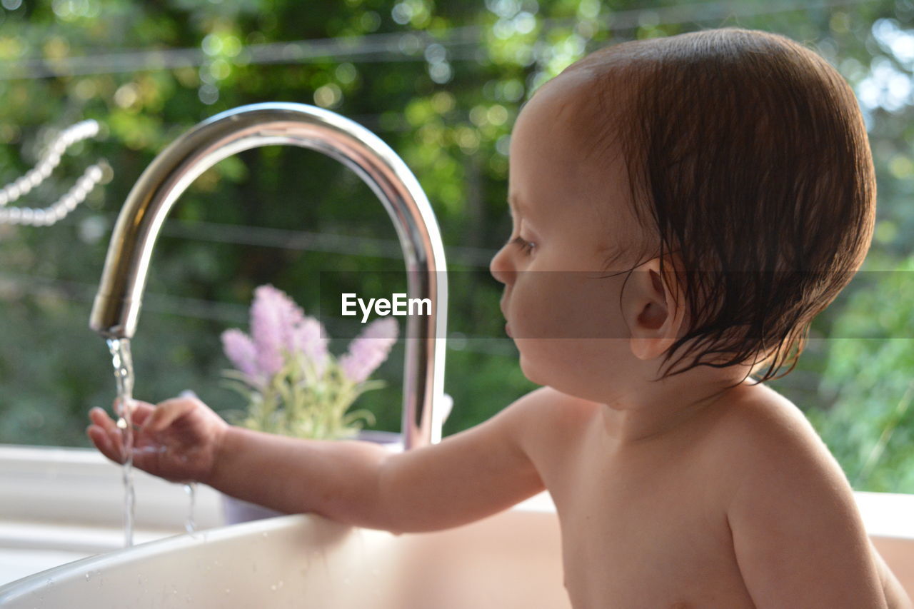 Boy washing hands under faucet