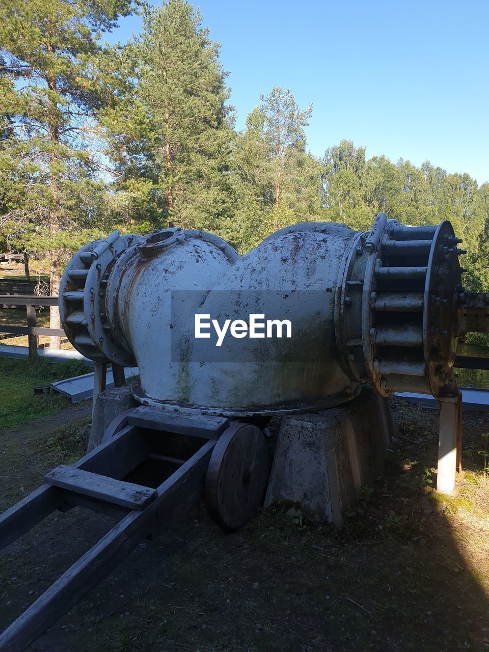 OLD MACHINERY ON FIELD AGAINST TREES