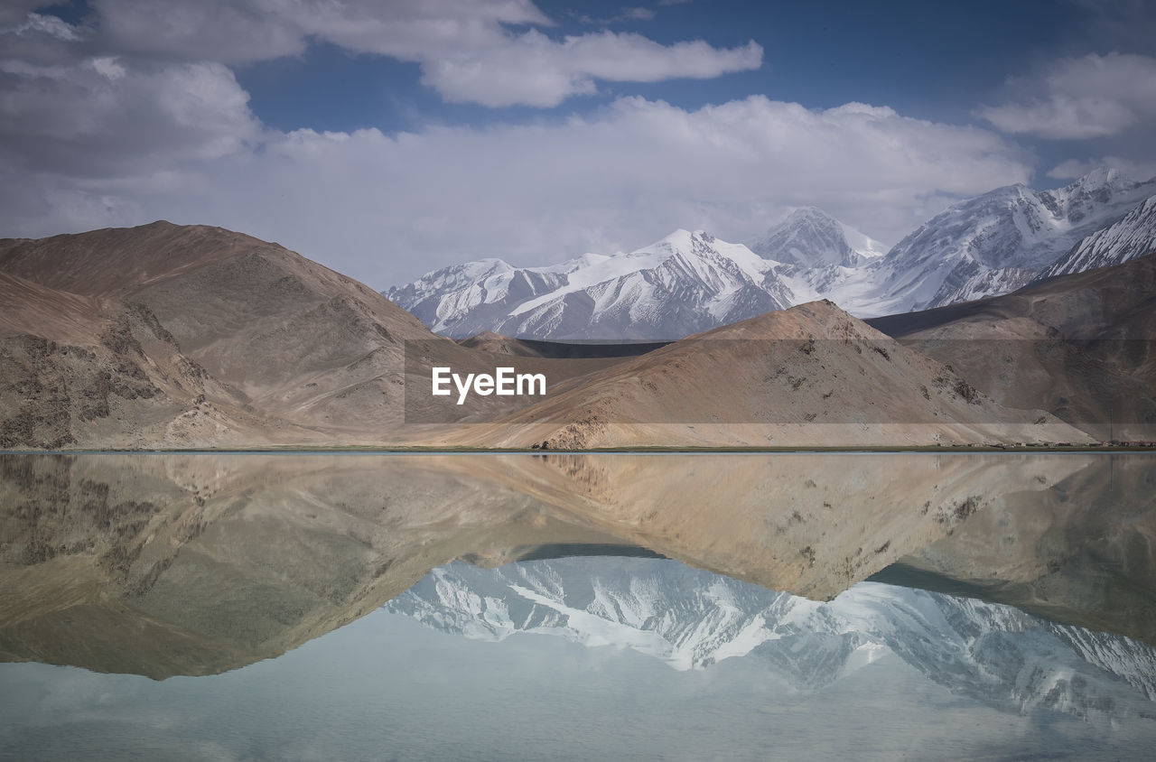 Reflection of mountain on karakul lake against sky