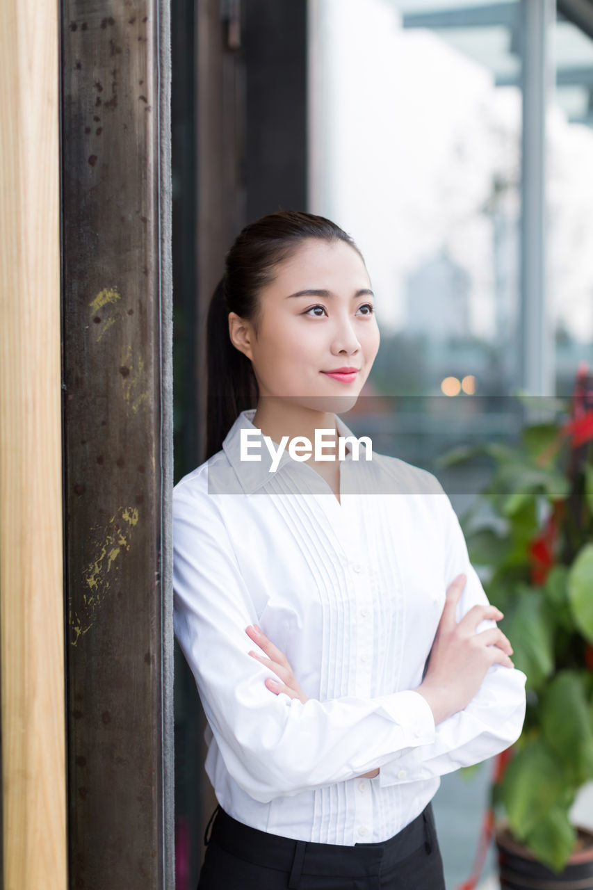 Smiling businesswoman with arms crossed standing outdoors