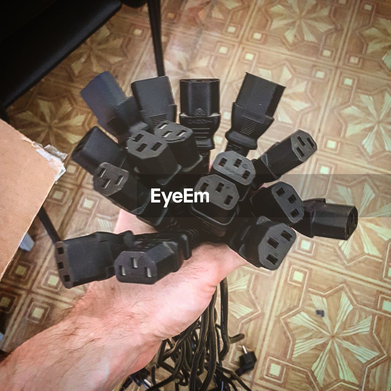 Cropped hand of man holding computer cables at office